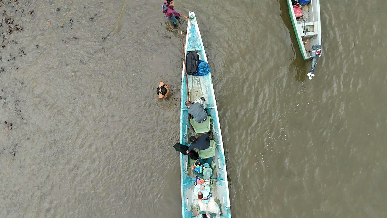 Canoes on a brown river in the rain, seen from above