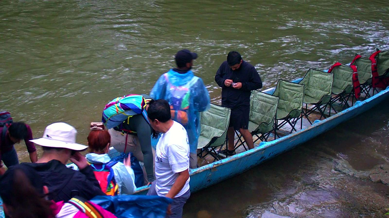 Volunteers in rain gear loading into a long canoe