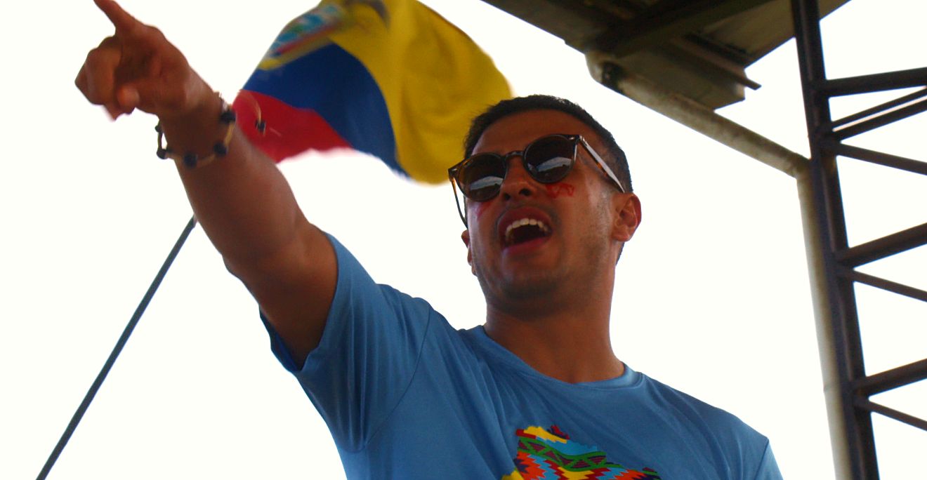 A Guild volunteer pointing beneath the Ecuadorian flag