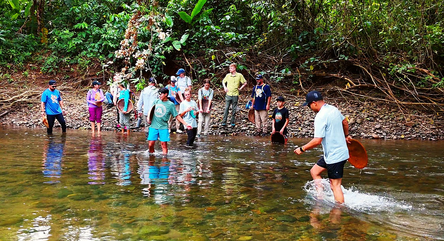 Volunteers wading into the river with gold pans