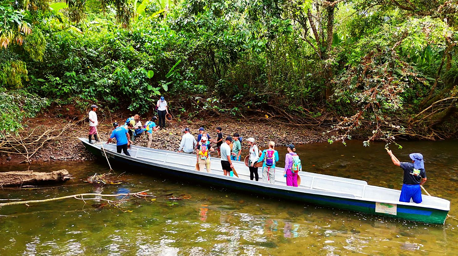 The group climbing out of a long canoe at the riverbank